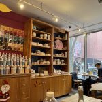 Rustic wooden shop interior with shelves of goods, artwork on the wall, and natural light.
