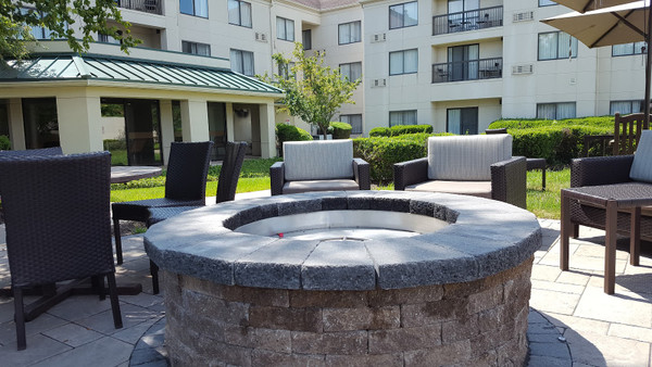 Stone fire pit surrounded by comfortable outdoor seating in a modern apartment complex courtyard.
