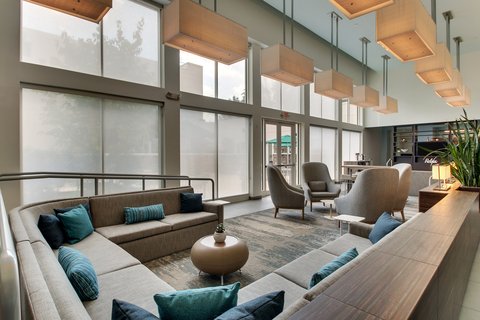 Modern, bright hotel lobby with comfortable seating areas and large windows.