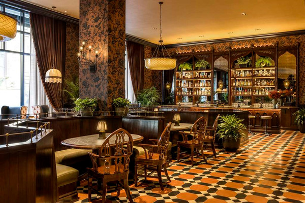 Elegant bar interior with dark wood, patterned walls, and checkerboard tile floor.