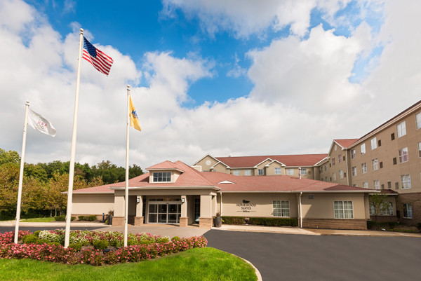 Hotel exterior with American flag flying under a partly cloudy blue sky.