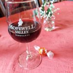 Red wine in a glass on a pink tablecloth with small decorative items.
