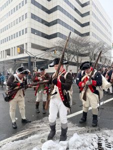 Revolutionary War reenactors march through downtown Trenton during a snowy Patriots Week 2025 reenactment.