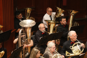 Musicians from the Blawenburg Band perform in a concert setting, playing brass instruments including tubas and French horns during a live community music performance.